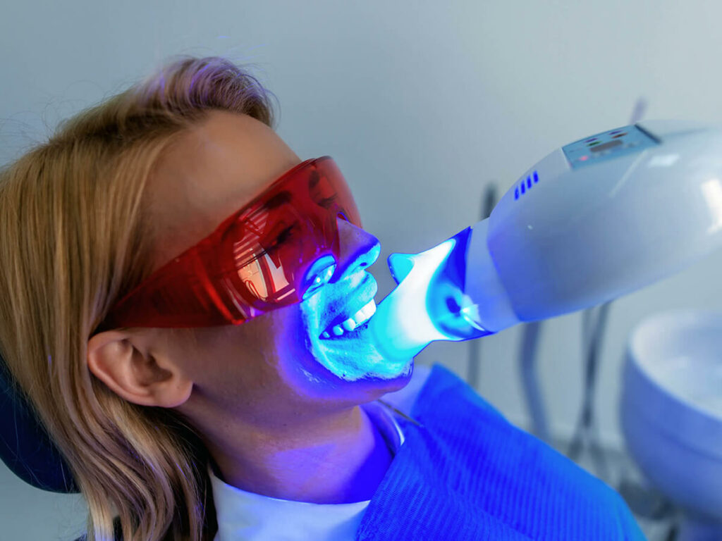 woman sitting in a chair receiving teeth whitening treatment
