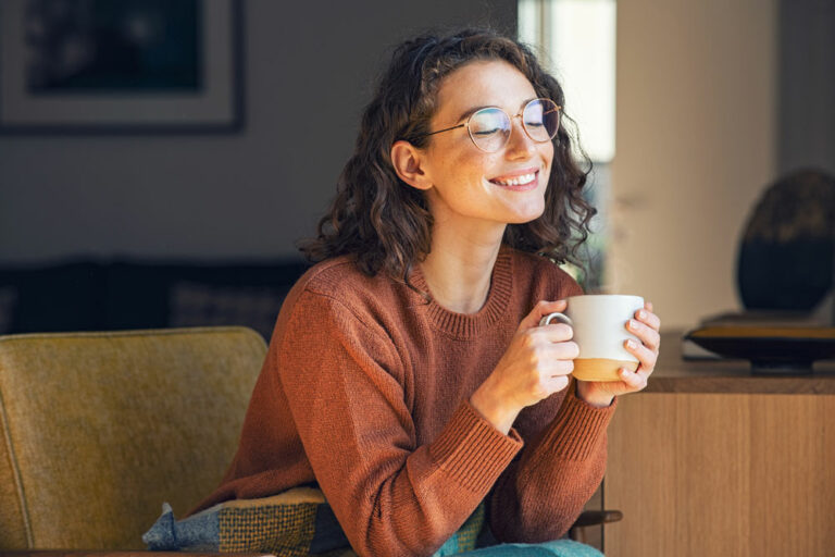 a women sitting, smiling with a cup of coffee